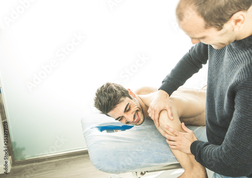 Chiropractor massaging a young man shoulder. Concept of physiotherapy