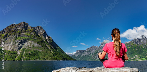 Frau sitzt an einem Fjord