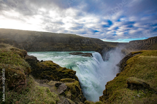 Widok na wodospad w Islandii. Woda przepływa z góry na dół.
