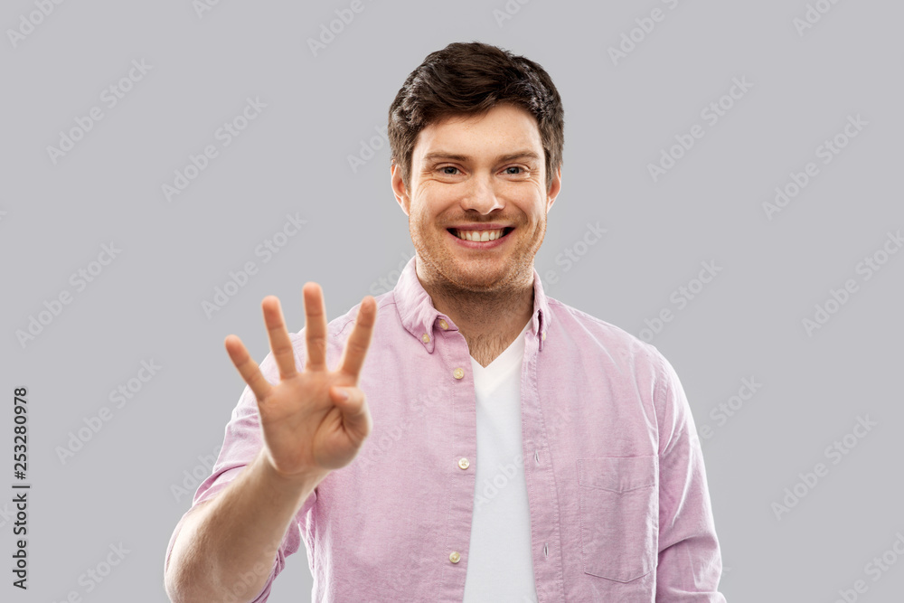 count and people concept - smiling young man showing four fingers over grey background count and people concept - smiling young man showing four fingers over grey background