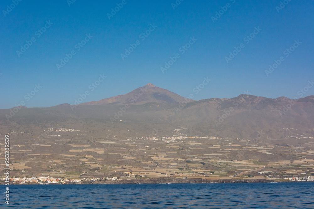 Teide volcano raising above coastal landscape - view form boat. Teide volcano raising above coastal landscape - view form boat.