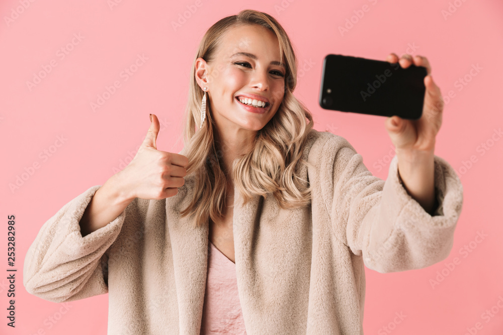 Young pretty woman posing isolated over pink wall background take a selfie by mobile phone. Young pretty woman posing isolated over pink wall background take a selfie by mobile phone.