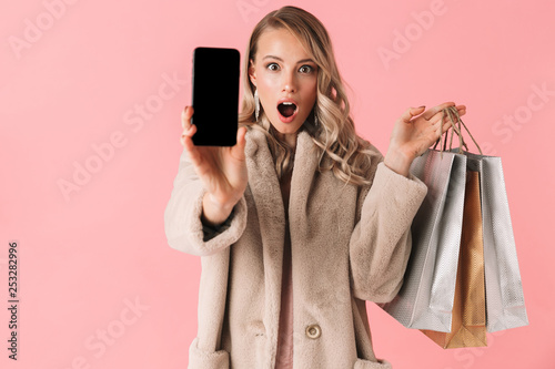 Beautiful young pretty woman posing isolated over pink wall background showing display of mobile phone.