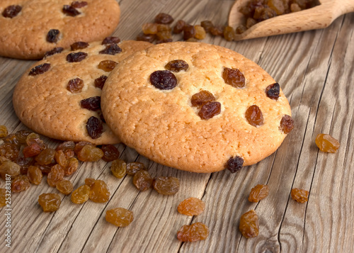 Oatmeal cookies with raisins, on a dark wooden background with a wooden spoon