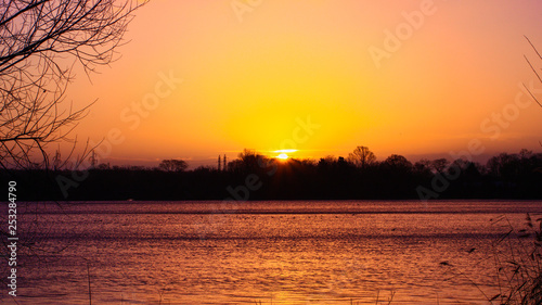 Bright sun in a clear sky in the countryside. Sunrise without clouds over the water