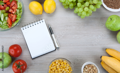 notebook with a diet nutrition with fresh vegetables and fruits on the table
