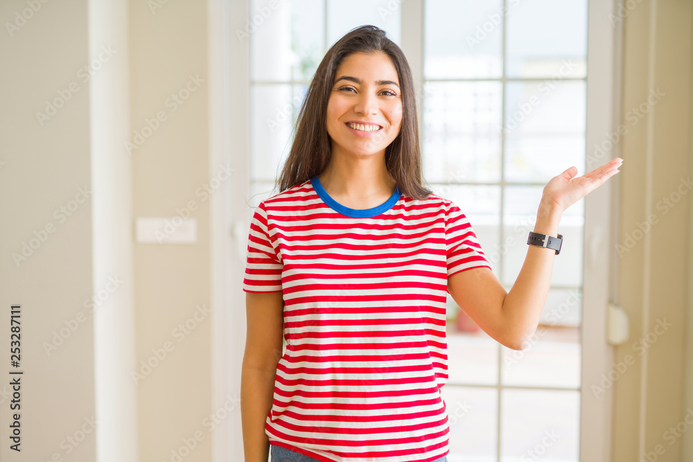 Young beautiful woman wearing casual t-shirt smiling cheerful presenting and pointing with palm of hand looking at the camera. Young beautiful woman wearing casual t-shirt smiling cheerful presenting and pointing with palm of hand looking at the camera.