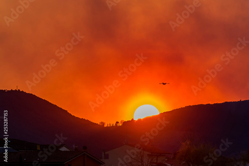 Canadair propeller plane flies over a town against a beautiful sunset