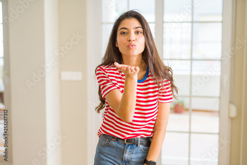 Young beautiful woman wearing casual t-shirt looking at the camera blowing a kiss with hand on air being lovely and sexy. Love expression.