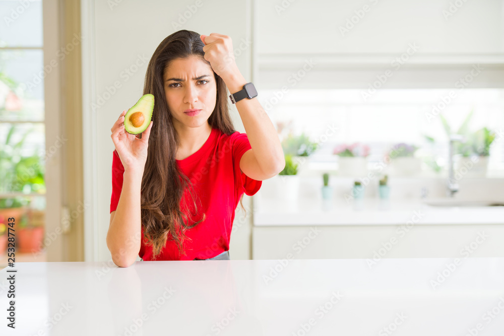 Young woman eating healthy avocado annoyed and frustrated shouting with anger, crazy and yelling with raised hand, anger concept Young woman eating healthy avocado annoyed and frustrated shouting with anger, crazy and yelling with raised hand, anger concept
