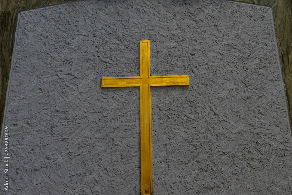 Golden Holy Cross against pale blue background