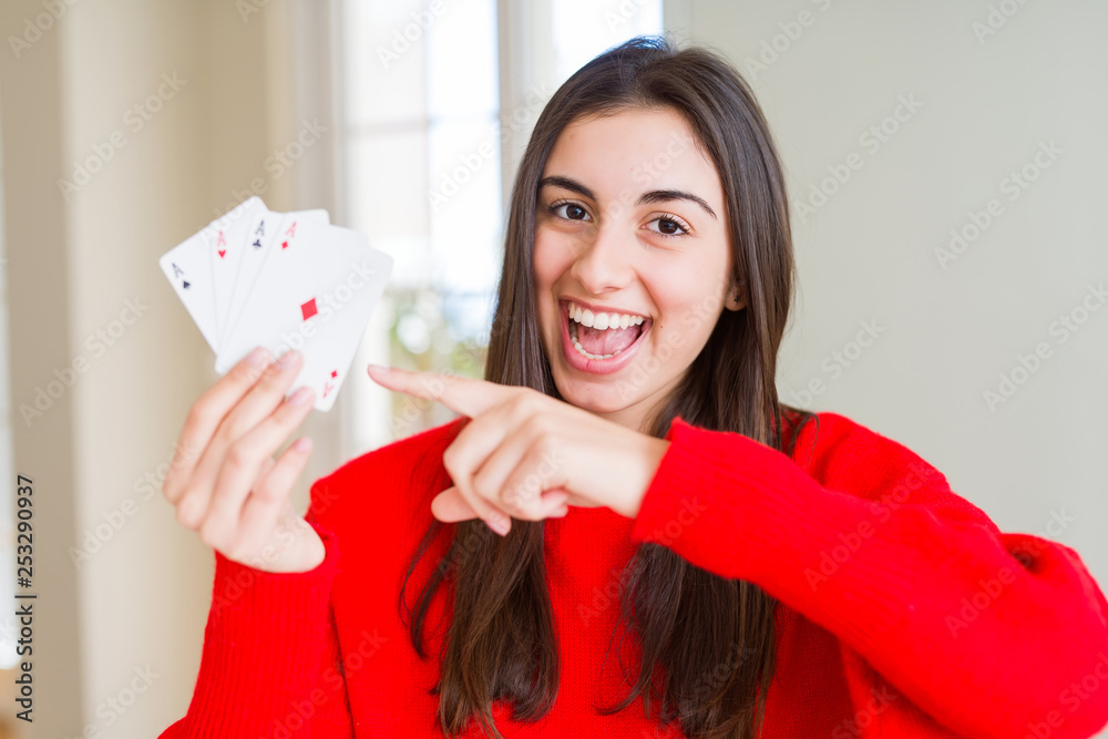 Beautiful young woman gambling playing poker very happy pointing with hand and finger Beautiful young woman gambling playing poker very happy pointing with hand and finger
