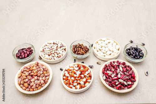 Assortment of beans on a stone background. Crimson cranberry, red, painted pony, black turtle, brown, black-eyed, Jacob's Cattle (heirloom) and lima.