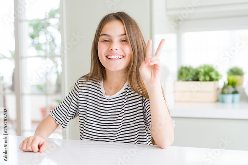 Beautiful young girl kid wearing stripes t-shirt showing and pointing up with fingers number two while smiling confident and happy.