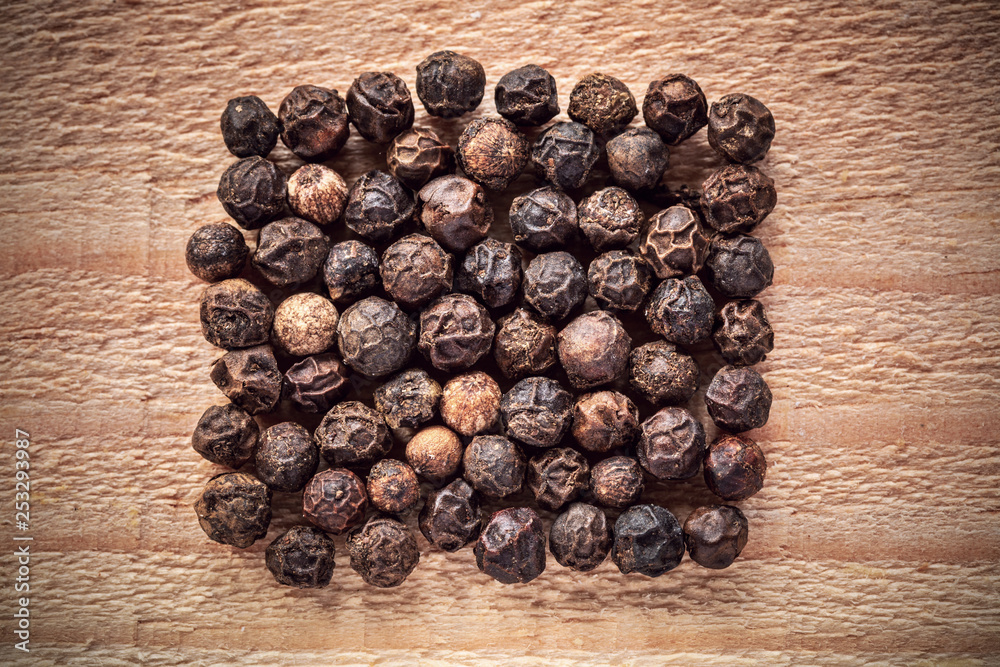 Obraz premium Black peppercorn closeup on wooden surface