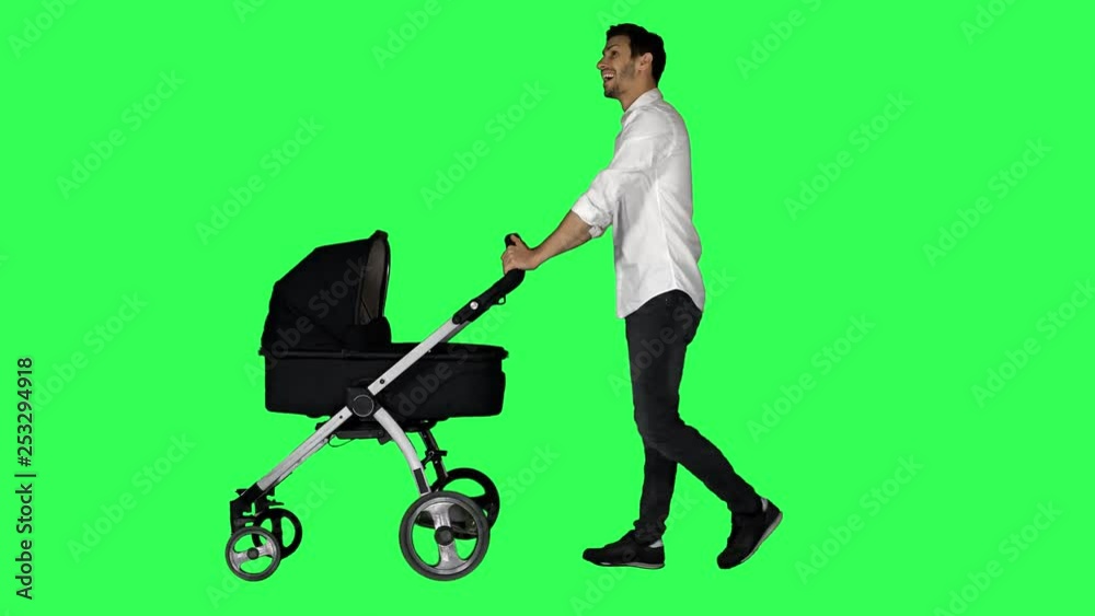 A dad walking with a stroller, looking around and at his baby, smiling ...