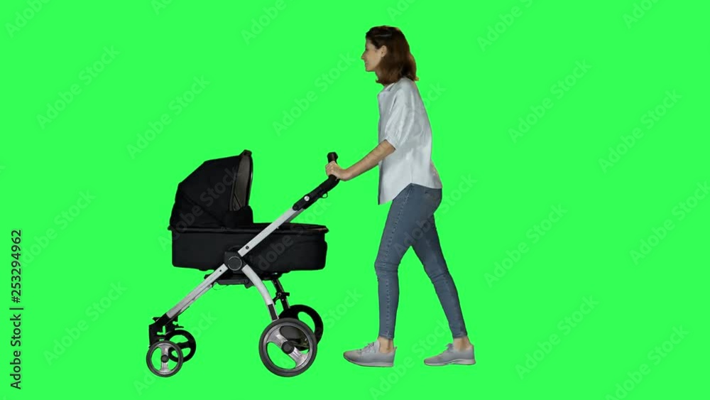 Mother walking with a stroller, looking around and to the camera, waving hello and smiling. Casual look, over green screen. Mother walking with a stroller, looking around and to the camera, waving hello and smiling. Casual look, over green screen.
