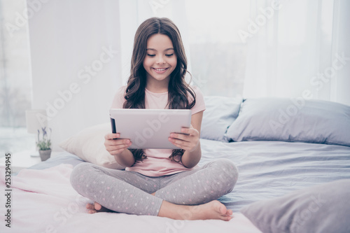 Close up photo cute beautiful she her little girl e-book hands observe telegram skype instagram millennial curly wavy wear home t-shirt pants comfortable apartments flat bright light colored room