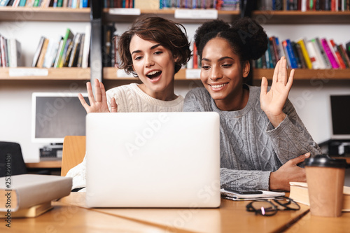 Two cheerful young girls students studying