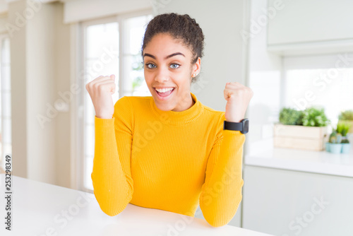 Beautiful young african american woman with afro hair celebrating surprised and amazed for success with arms raised and open eyes. Winner concept.