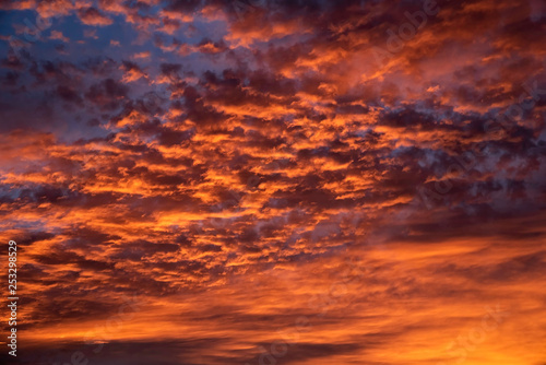 Fototapeta Naklejka Na Ścianę i Meble -  A majestic and awe-inspiration combination of deep blue sky and fiery orange and yellow clouds at sunset.