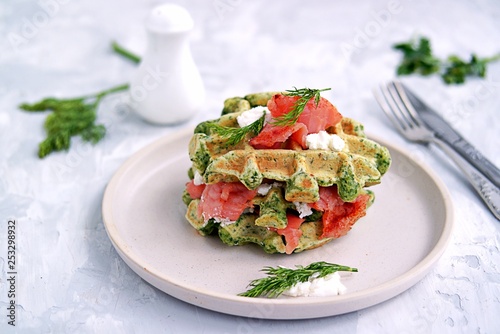 Light dinner, lunch or lunch, savory spinach snack waffles with salted salmon and cream cheese on a ceramic plate