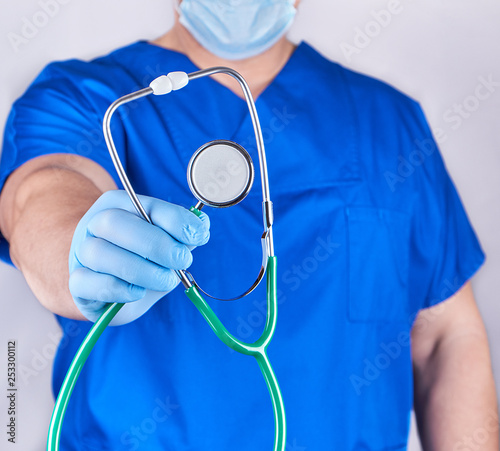 doctor in blue uniform and latex gloves holding a stethoscope