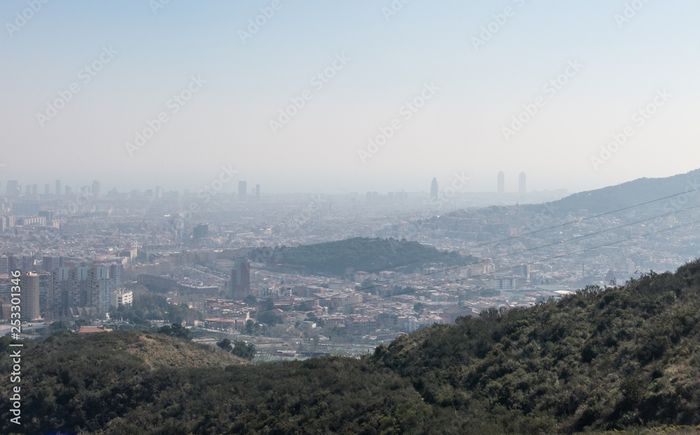 Overview of the polluted city of Barcelona, from the Collserola mountain, with a layer of smog over it.