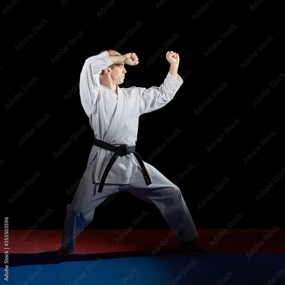 Athlete trains formal karate exercises on red and blue tatami