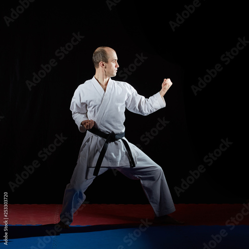  Adult athlete doing formal karate exercises on red and blue tatami