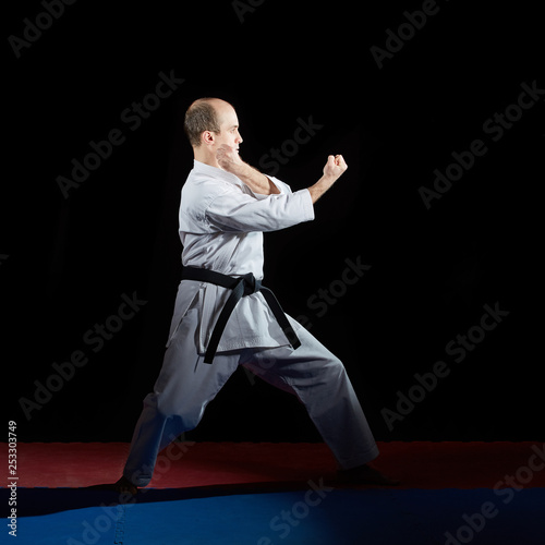 Athlete doing formal karate exercises on red and blue tatami