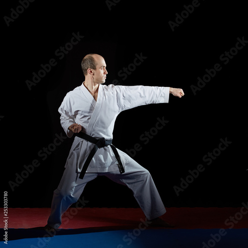 Athlete performs formal karate exercises on red and blue tatami