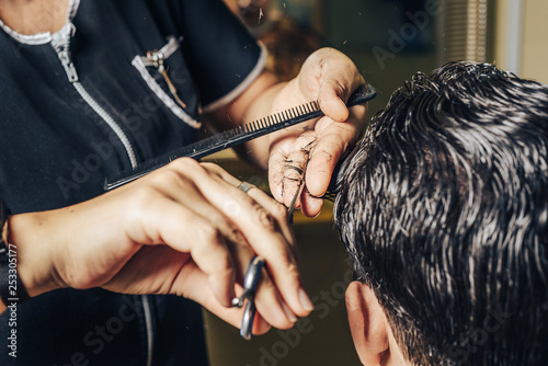 A professional hairdresser makes the design of the head, cuts hair with scissors. Beauty shop. Male beauty. 
