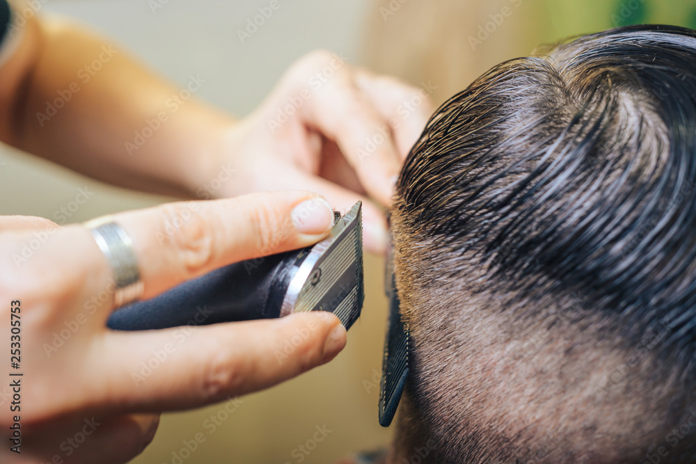 Fototapeta premium A professional hairdresser makes the design of the head, shave your head electric razor. Beauty shop. Male beauty. 