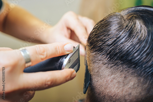A professional hairdresser makes the design of the head, shave your head electric razor. Beauty shop. Male beauty. 
