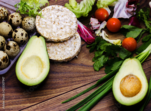 Slices of avocado on a wooden background, gluten-free bread, salad, green onions. Quail eggs. Healthy food. Vegetables and Vegetarian Food.