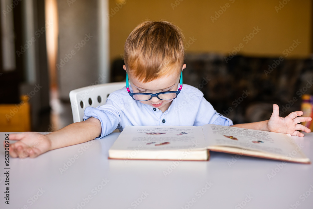 cute boy, kid with special needs looking at a book, in rehabilitation center cute boy, kid with special needs looking at a book, in rehabilitation center