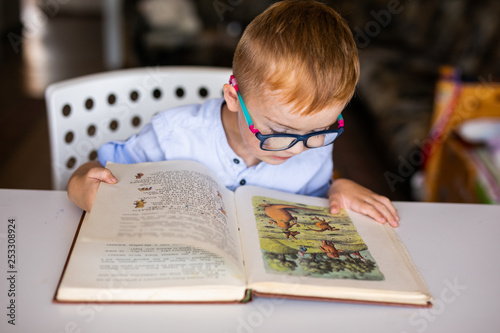 Fotografi cute boy, kid with special needs looking at a book, in rehabilitation center