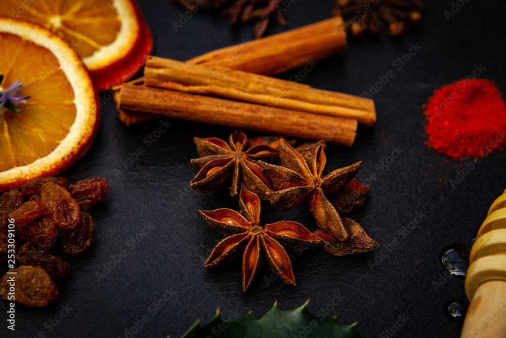spices for mulled wine recipe, cinamon, star anis, dry oranges, cloves, red chili pepper powder over black background spices for mulled wine recipe, cinamon, star anis, dry oranges, cloves, red chili pepper powder over black background