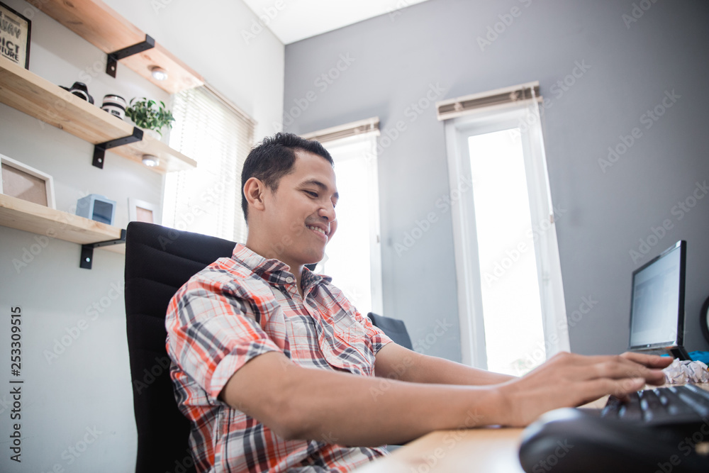 asian man enjoy his time working in the home office by himself