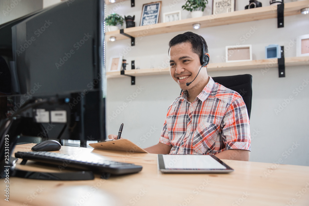 asian tele marketing on duty talk via phone to his customer in the office asian tele marketing on duty talk via phone to his customer in the office