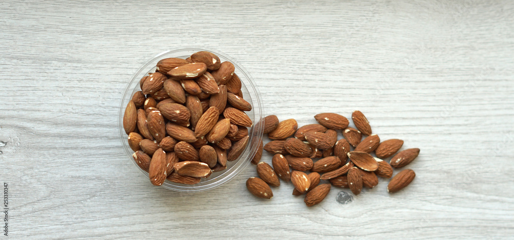 Healthy food for background image close up almond nuts. Texture on white grey table top view. Nut on the cup plate Healthy food for background image close up almond nuts. Texture on white grey table top view. Nut on the cup plate