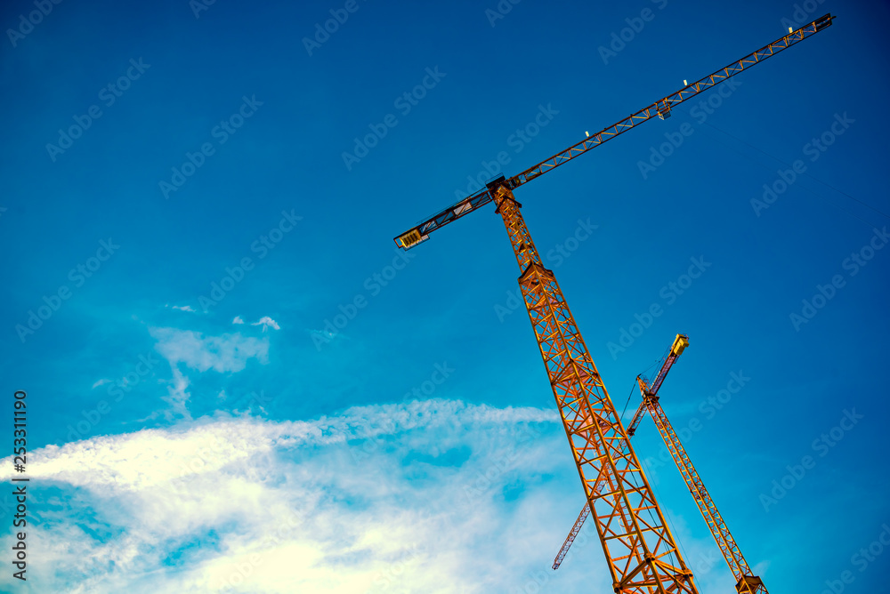 Detail of tower cranes isolated blue sky background.