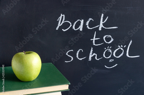 Fototapeta Naklejka Na Ścianę i Meble -  Inscription text Back to school on black chalkboard and green Apple on stack books textbooks, Concept education