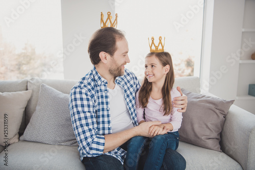 Portrait of his he her she nice lovely sweet attractive cheerful cheery pre-teen girl bearded dad daddy sitting on divan looking at each other in light white interior room indoors