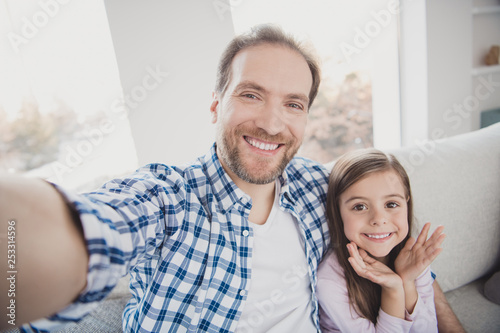Self-portrait of his he her she nice cute lovely attractive winsome pre-teen cheerful positive girl handsome bearded daddy sitting on divan fashion blog blogger in light white interior room indoors