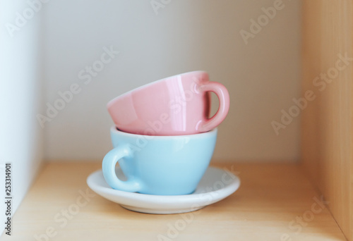 Ceramic cups blue and pink on a wooden shelf