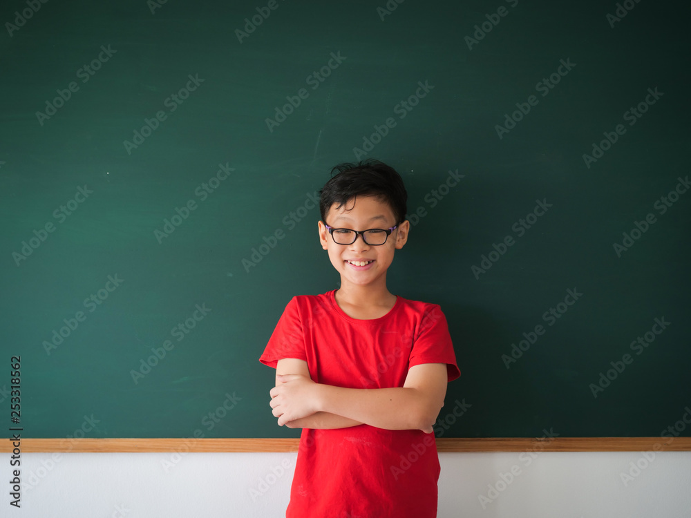 Asian boy with book on blackboard background education school classroom concept