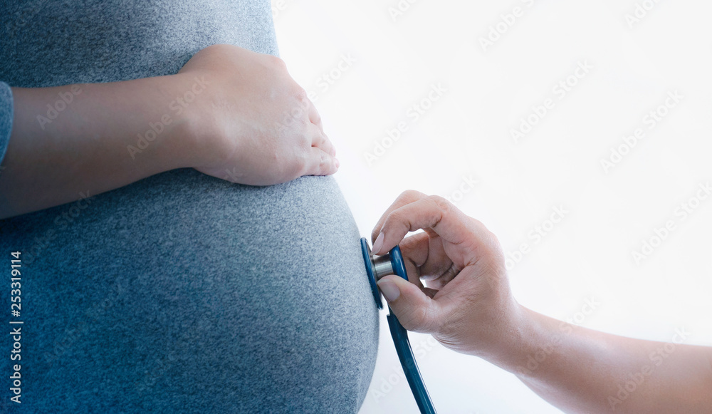 Fototapeta premium Close up doctor checking belly of pregnant woman with stethoscope.