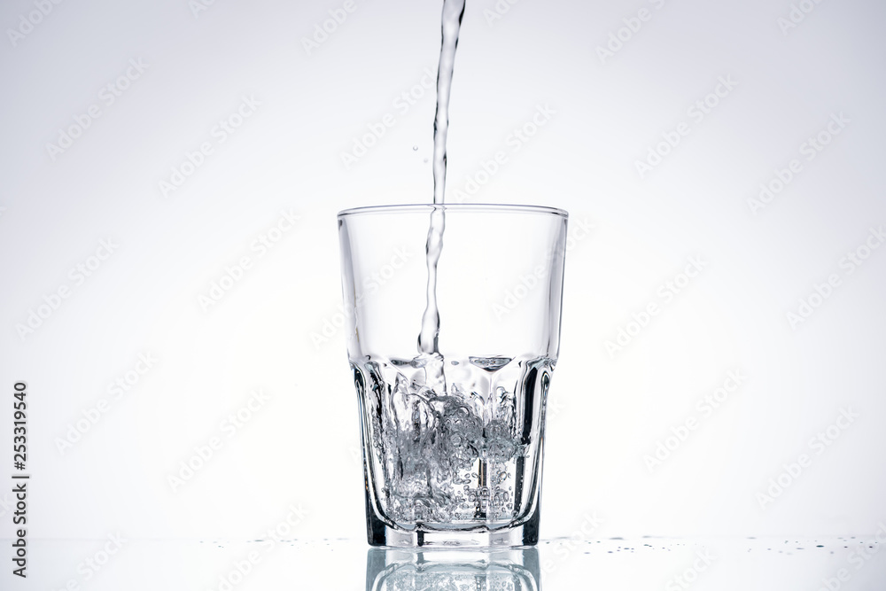 background of water pouring in glass on white with backlit background of water pouring in glass on white with backlit